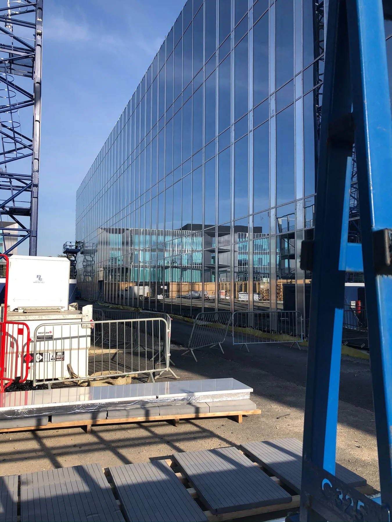 Fatada vitrata ampla pe santier comercial, cu echipamente de acces.